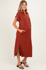 woman wearing a rust-colored maternity polo dress with pockets and side slits, showcasing her baby bump