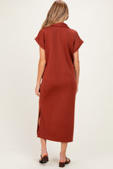 woman wearing a rust-colored maternity maxi dress with short sleeves and side slits, seen from the back