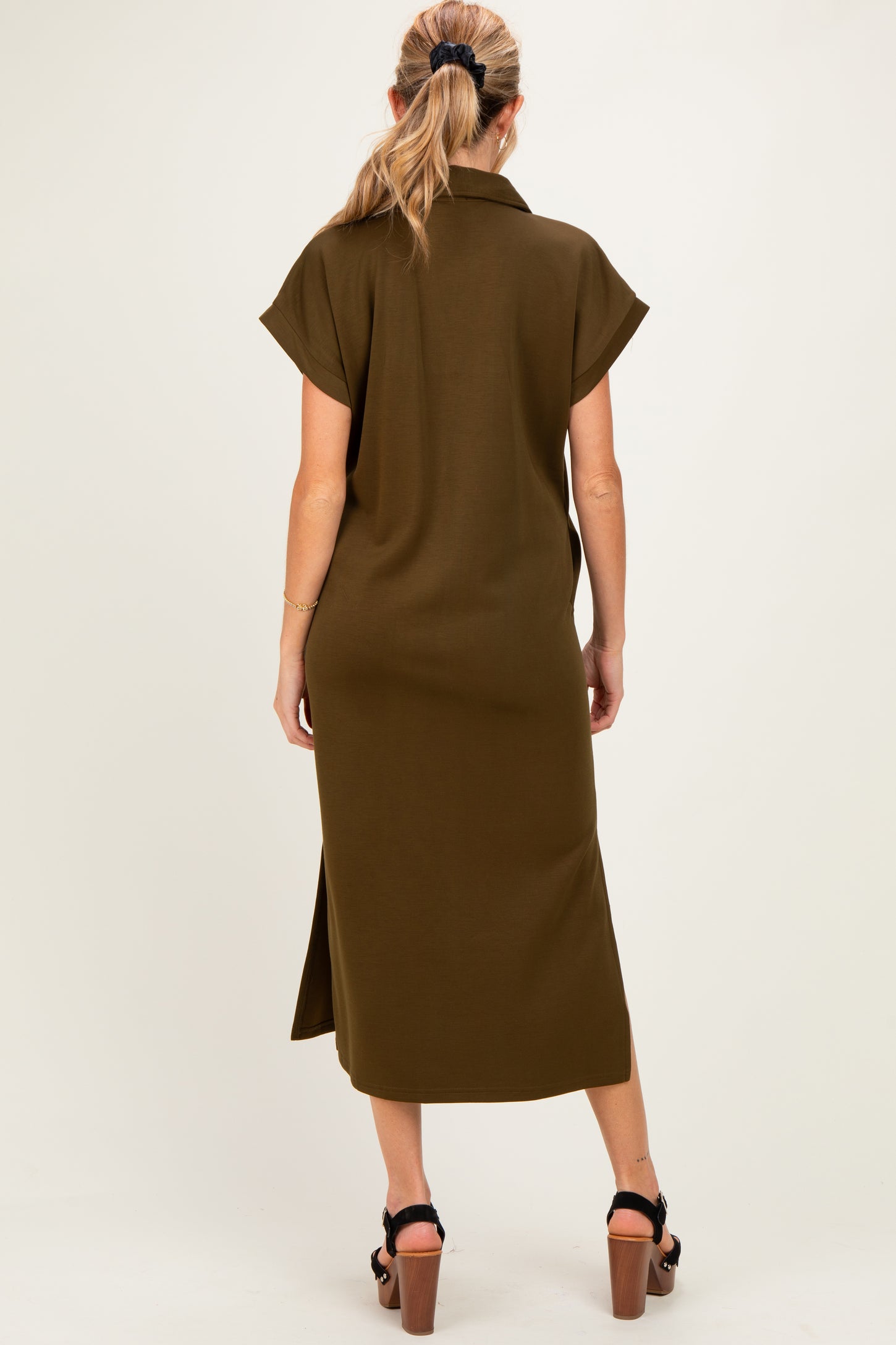 woman wearing an olive green short sleeve maternity dress with a back slit, showing a baby bump