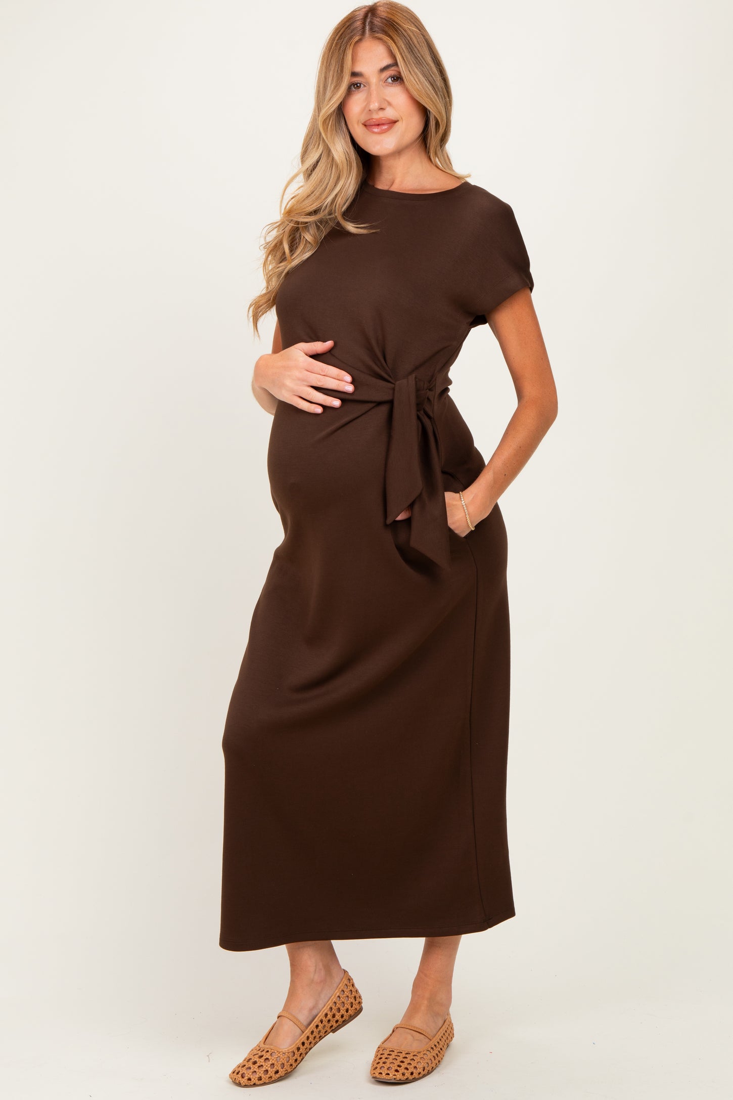 woman wearing a brown maternity maxi dress with a tie waist and a visible baby bump
