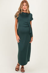 woman wearing a dark green maternity maxi dress with a tie detail, highlighting her baby bump