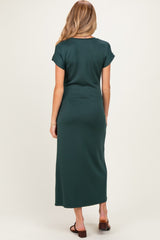 woman wearing a dark green maternity maxi dress, showcasing a fitted silhouette from the back