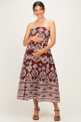 woman wearing a brown and white strapless maternity dress while gently holding her baby bump