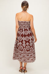 woman wearing a brown strapless maternity maxi dress with white floral patterns, showing her baby bump