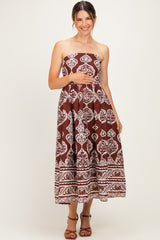 woman wearing a brown strapless maternity maxi dress with white floral patterns and holding her baby bump