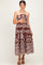woman wearing a brown strapless maternity maxi dress with white floral patterns and holding her baby bump