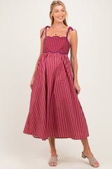 woman wearing a red and purple striped maternity dress with adjustable tie straps and a flowing skirt