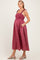 woman wearing a burgundy striped maternity dress with adjustable straps and pockets, showcasing a baby bump