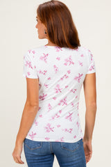 woman wearing a white short sleeve top with pink floral pattern and a fitted style, viewed from the back