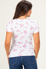 woman wearing a white maternity top with pink floral print and short sleeves, showing a fitted style from the back