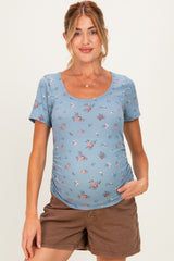 woman wearing a floral patterned blue maternity top with short sleeves and a gently curved hem, showcasing her baby bump