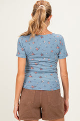 woman wearing a blue floral maternity top with short sleeves and brown shorts, showing a fitted style from the back