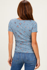 woman wearing a fitted blue floral short sleeve top, back view, paired with fitted blue jeans