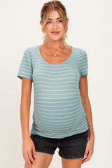 woman wearing a light green striped maternity top and showing her baby bump
