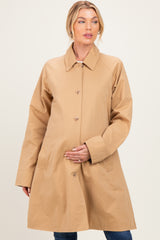 woman wearing a beige maternity coat with button closure and side pockets, holding her baby bump