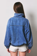 woman wearing a loose fit denim jacket with a high collar and elastic waistband, viewed from the back