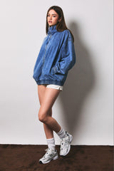 woman wearing an oversized denim jacket with elastic cuffs and shorts, styled with white socks and sneakers