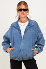 woman wearing a blue denim maternity jacket with a zip front and elastic cuffs, styled casually with sunglasses