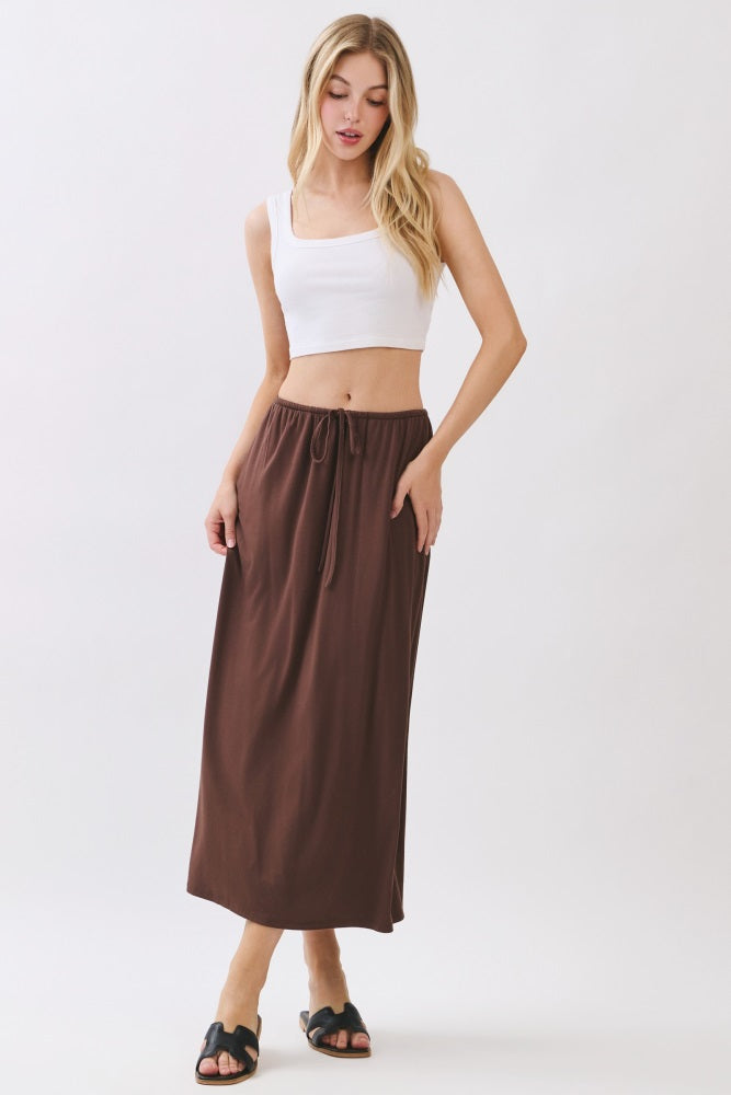 woman wearing a white crop top and a brown maxi skirt with a drawstring waist