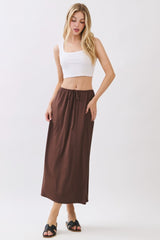woman wearing a white crop top and a brown maxi skirt with a drawstring waist