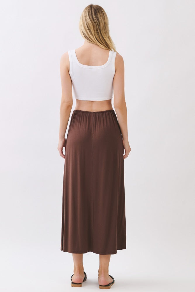 woman wearing a white crop top and a brown maxi skirt, seen from the back