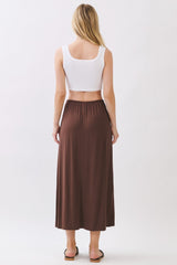 woman wearing a white crop top and a brown maxi skirt, seen from the back