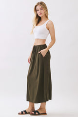 woman wearing a white cropped tank top and an olive green maxi skirt with pockets