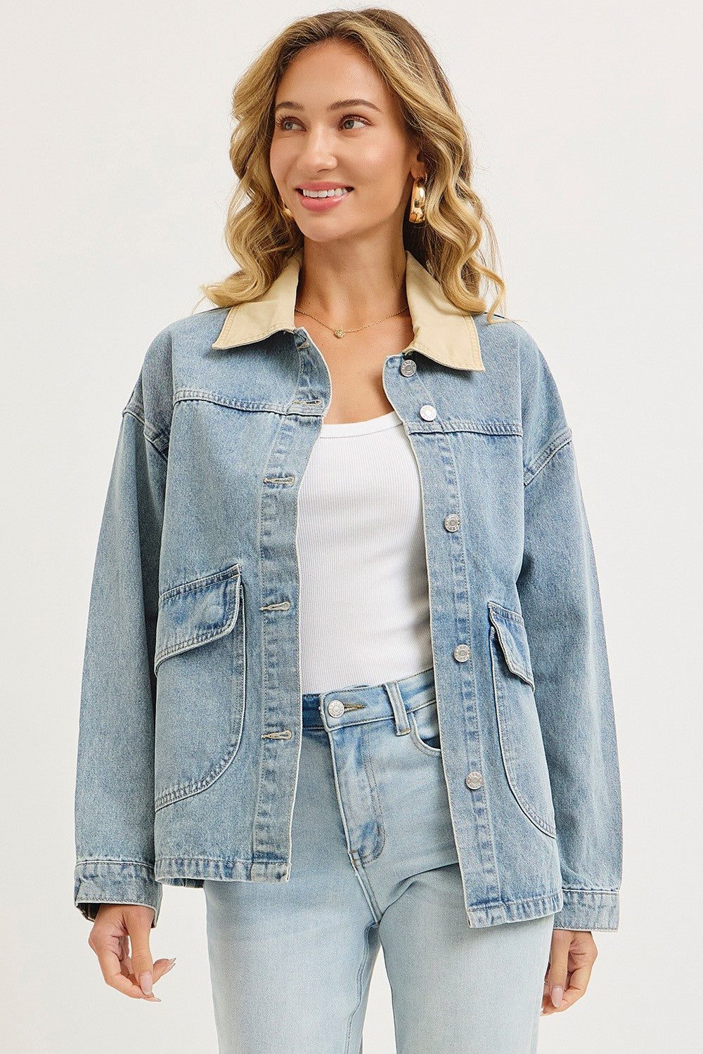 woman wearing a light blue denim jacket with a cream collar and front pockets, styled with a white top and light jeans