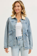 woman wearing a light blue denim jacket with a cream collar and front pockets, styled with a white top and light jeans