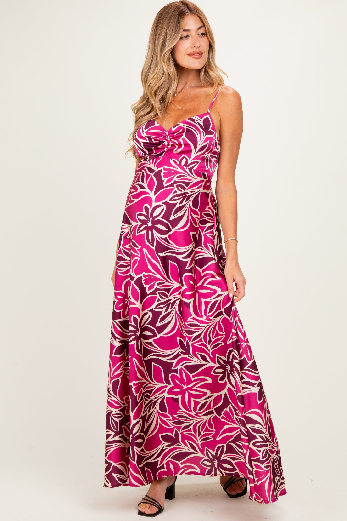 woman wearing a pink floral print maternity maxi dress, showcasing her baby bump with spaghetti straps and a flowing silhouette