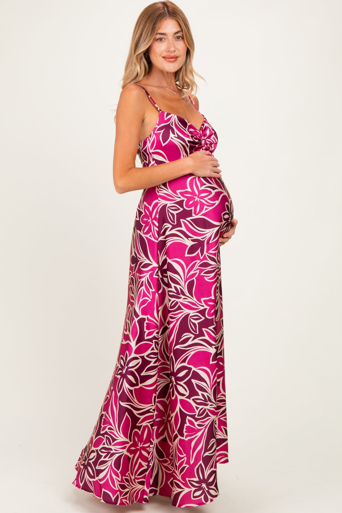 woman wearing a pink floral maternity maxi dress and holding her baby bump