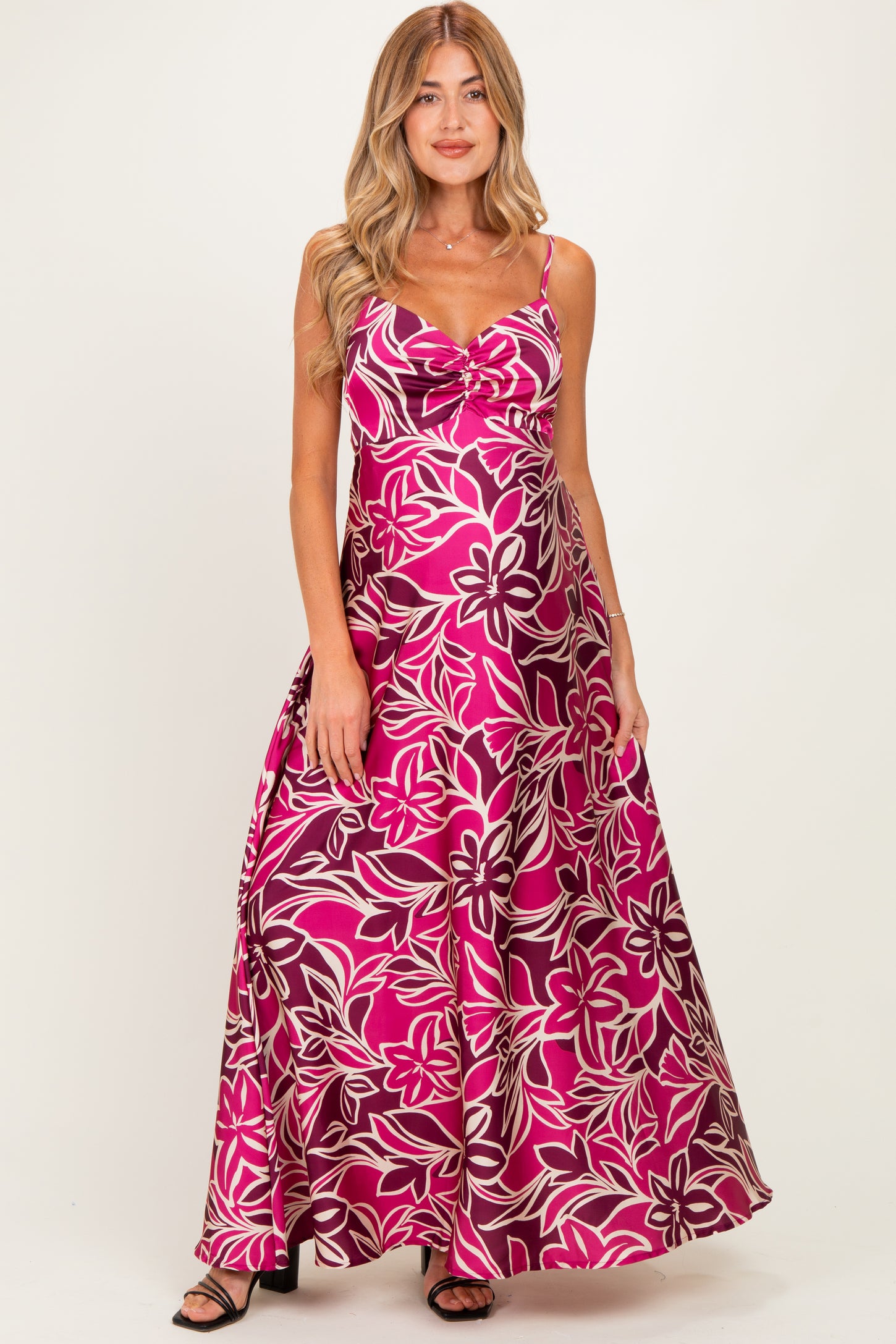 woman wearing a pink floral maternity maxi dress with a scoop neckline and adjustable straps, showcasing her baby bump