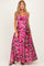 woman wearing a pink floral maternity maxi dress with a scoop neckline and adjustable straps, showcasing her baby bump