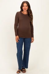 woman wearing a brown long sleeve maternity top and blue flare jeans with a visible baby bump