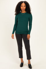 woman wearing a dark green long sleeve fitted top paired with black cropped jeans and slide-on mules