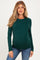 woman wearing a dark green long sleeve maternity top and showing her baby bump while smiling