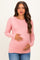 woman wearing a light pink long sleeve maternity top and holding her baby bump