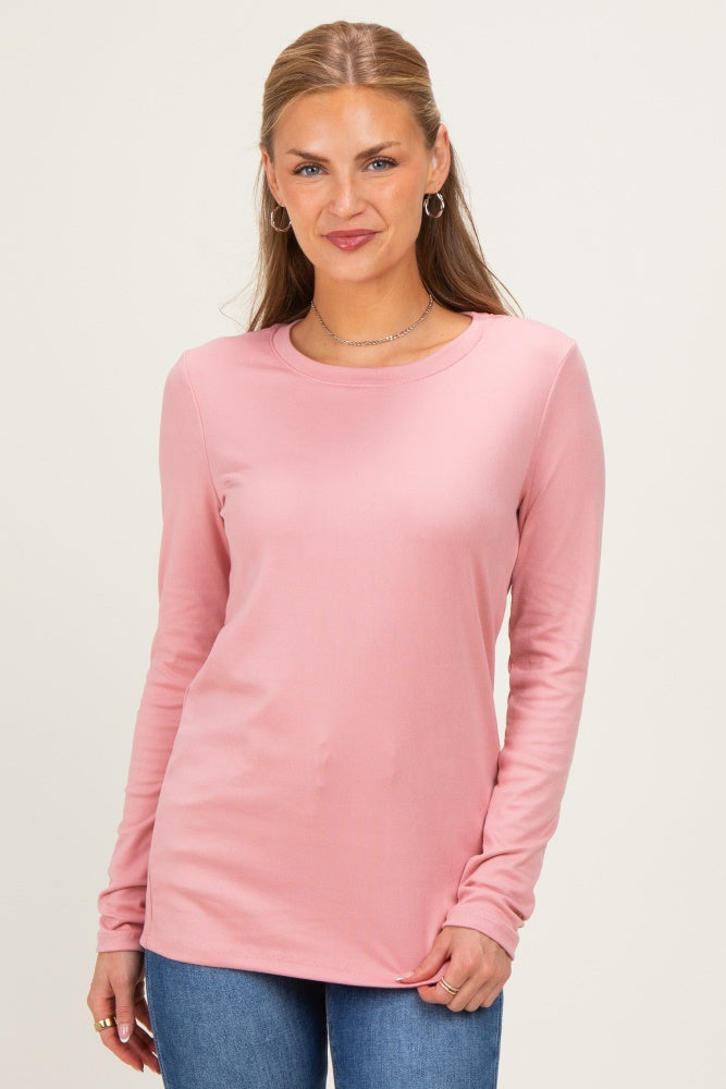 woman wearing a pink long sleeve top with a rounded neckline and relaxed fit paired with blue jeans