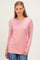 woman wearing a pink long sleeve top with a rounded neckline and relaxed fit paired with blue jeans