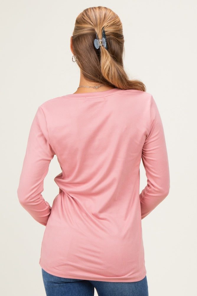 woman wearing a pink long sleeve top, view from the back with hair in a ponytail and casual style