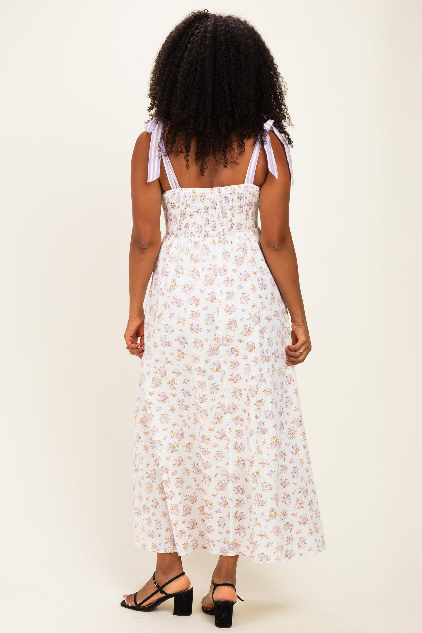 woman wearing a floral print maxi dress with back smocked detail and tied shoulder straps
