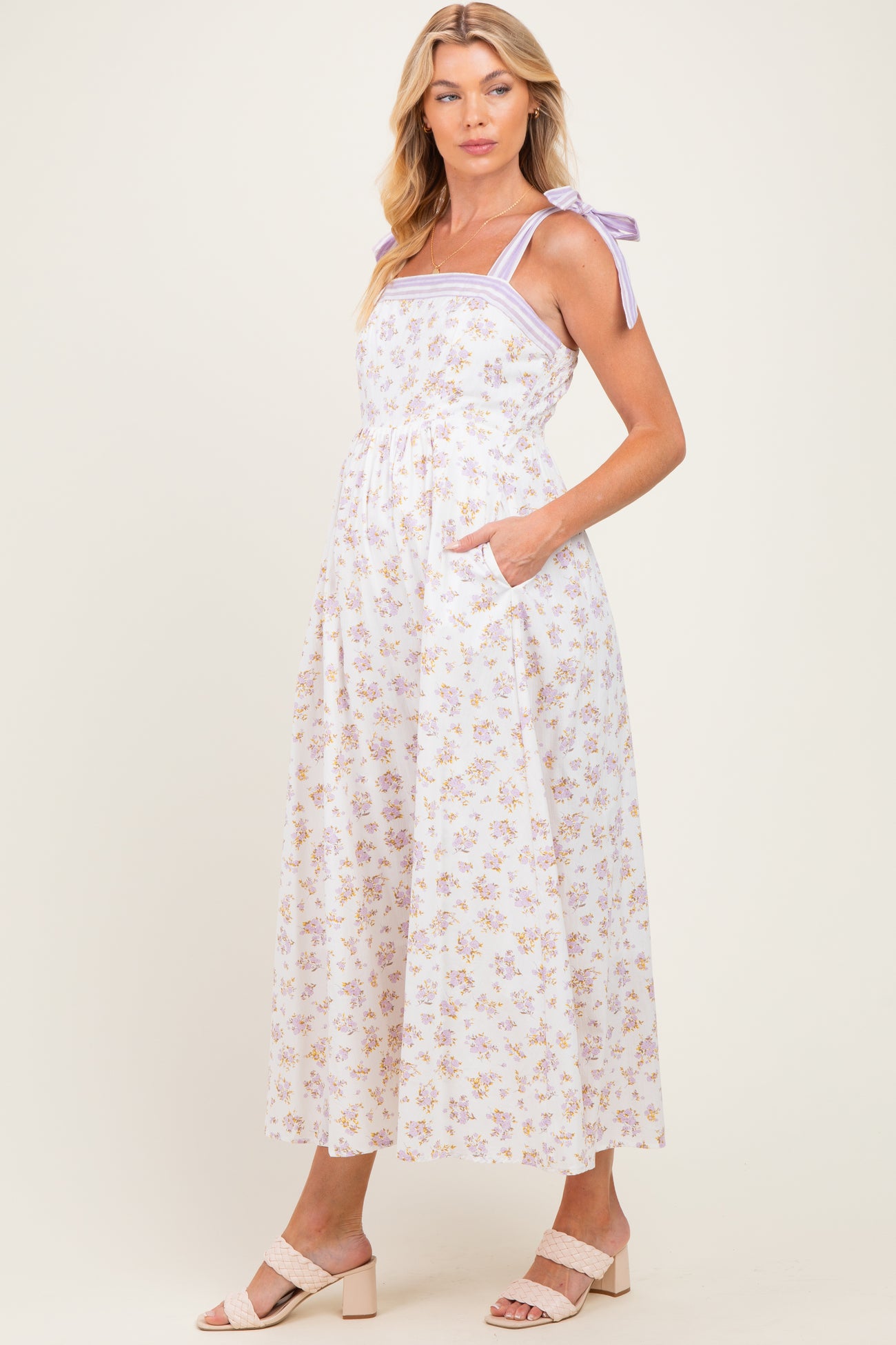 woman wearing a floral maternity maxi dress with purple tie straps and side pockets