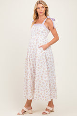 woman wearing a floral maternity maxi dress with purple tie straps and side pockets
