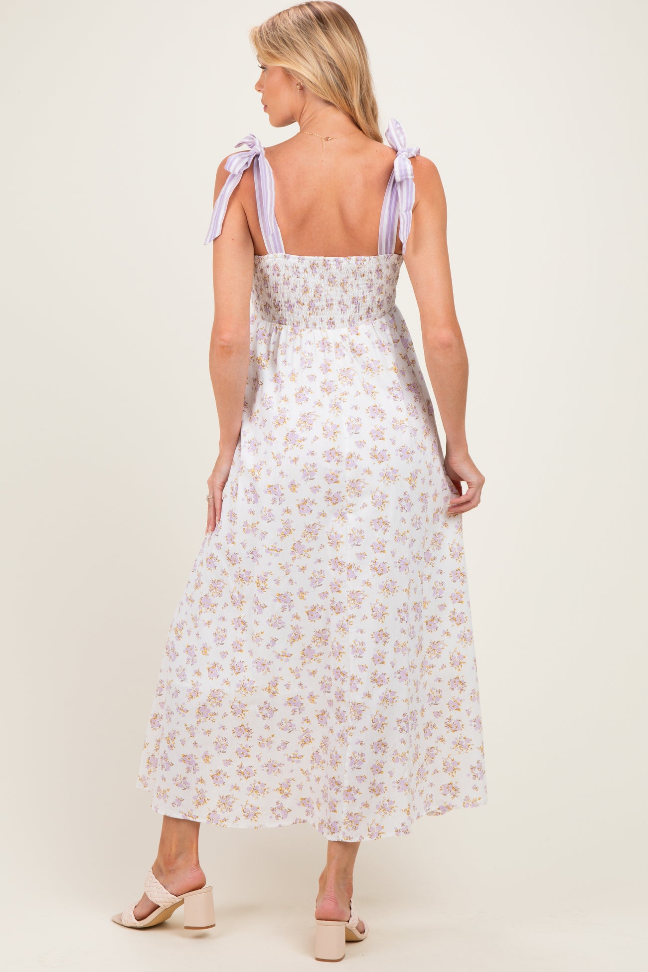 woman wearing a floral print maternity maxi dress with lavender tie straps and a smocked back, showing a baby bump