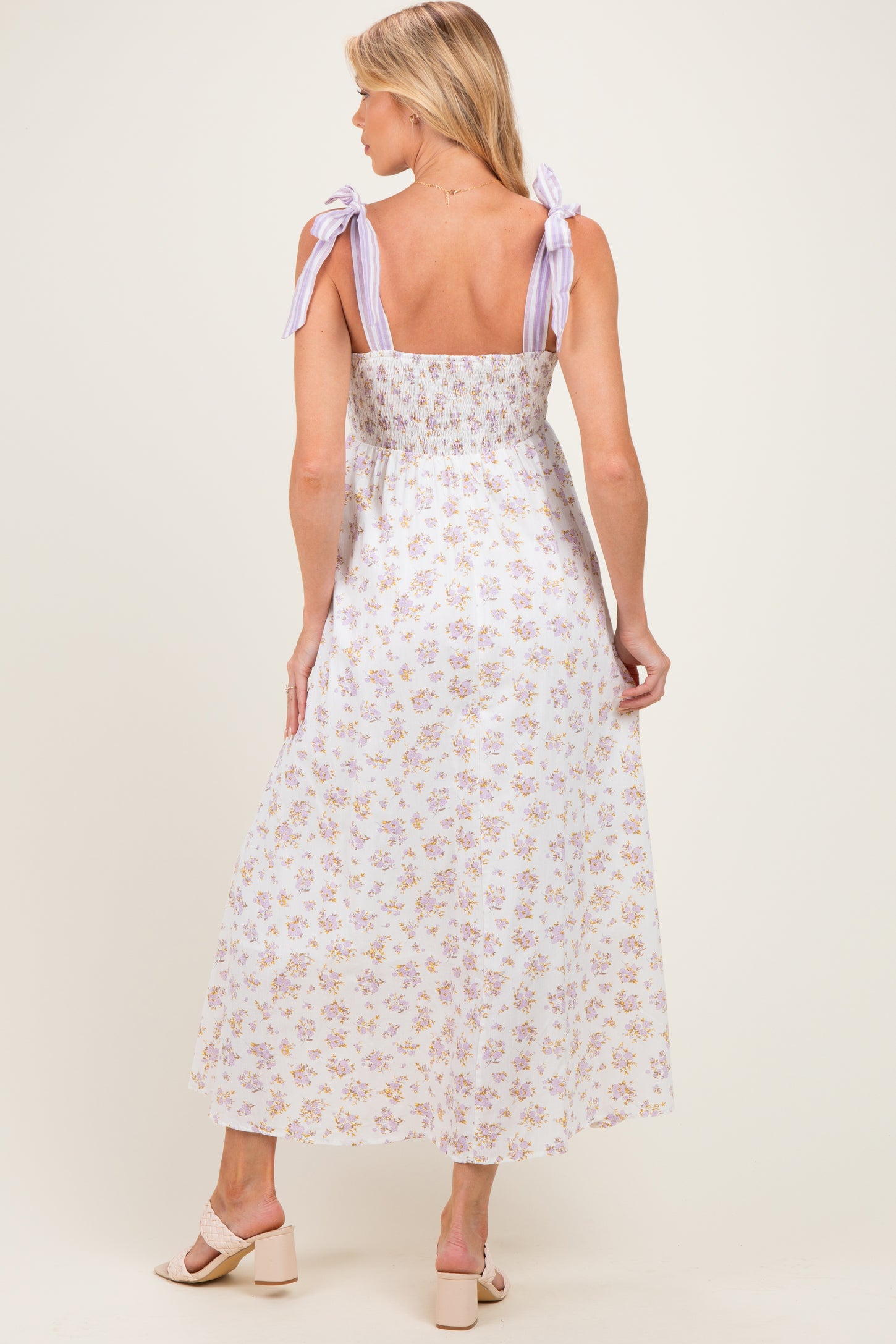 woman wearing a floral print maternity maxi dress with lavender tie straps and a smocked back, showing a baby bump