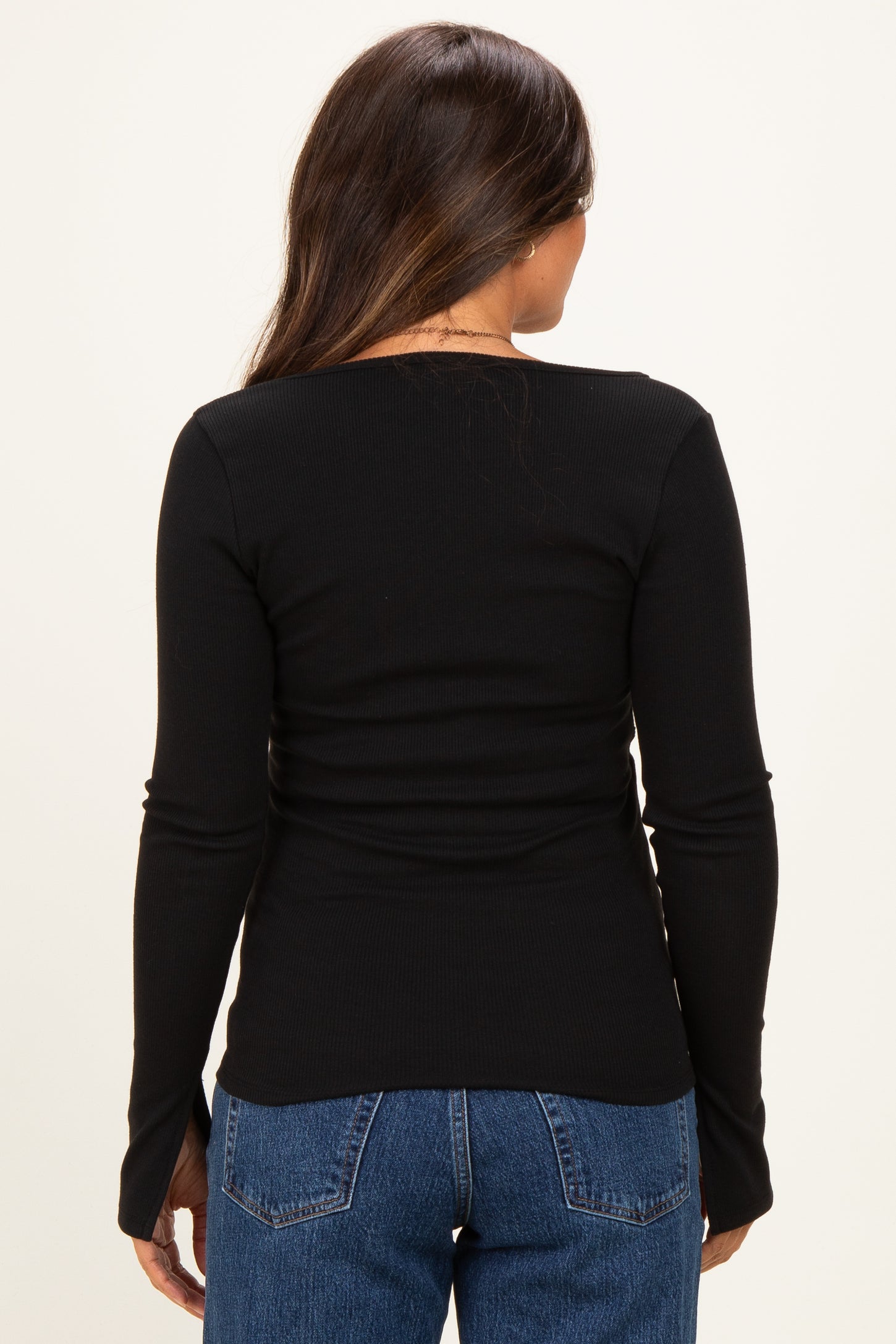 woman wearing a black long sleeve maternity top, showing the back view with a fitted style and ribbed texture