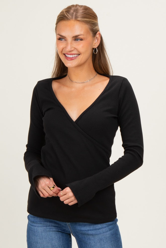 woman wearing a black long sleeve wrap top with a deep v-neckline and fitted style, paired with blue jeans