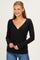 woman wearing a black long sleeve wrap top with a deep v-neckline and fitted style, paired with blue jeans