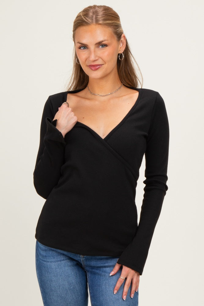 woman wearing a black long sleeve wrap top with a deep v-neck and fitted style, paired with blue jeans
