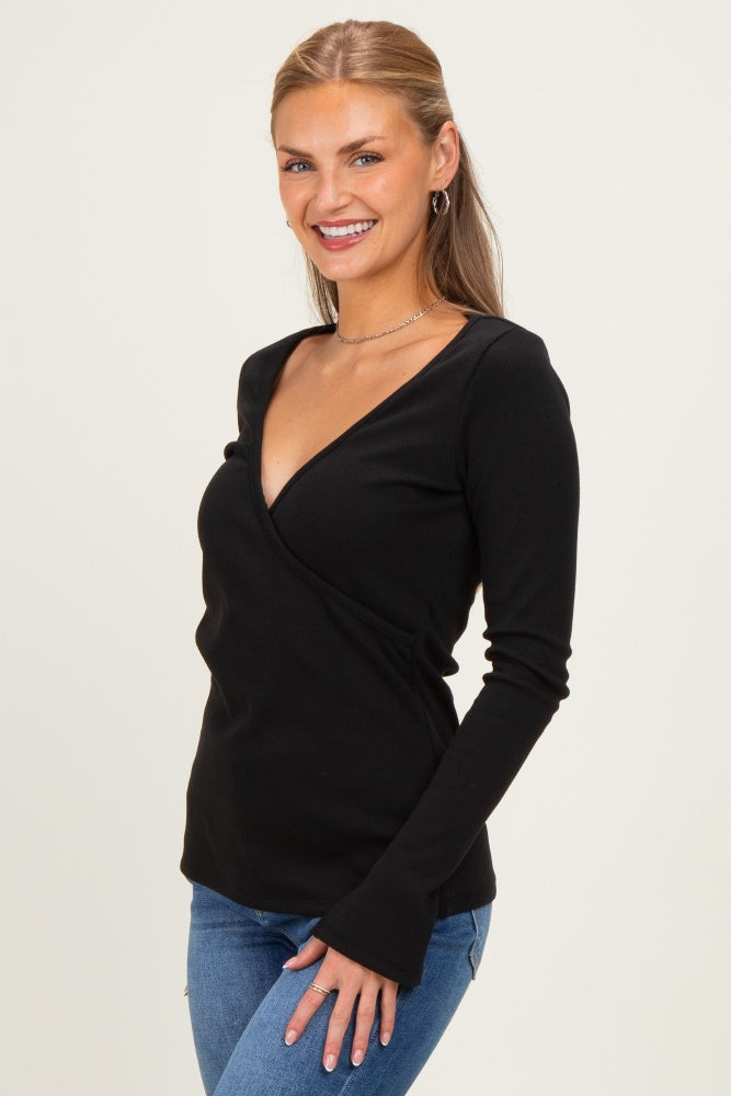 woman wearing a black long sleeve wrap top with a v-neck and fitted style, paired with blue jeans